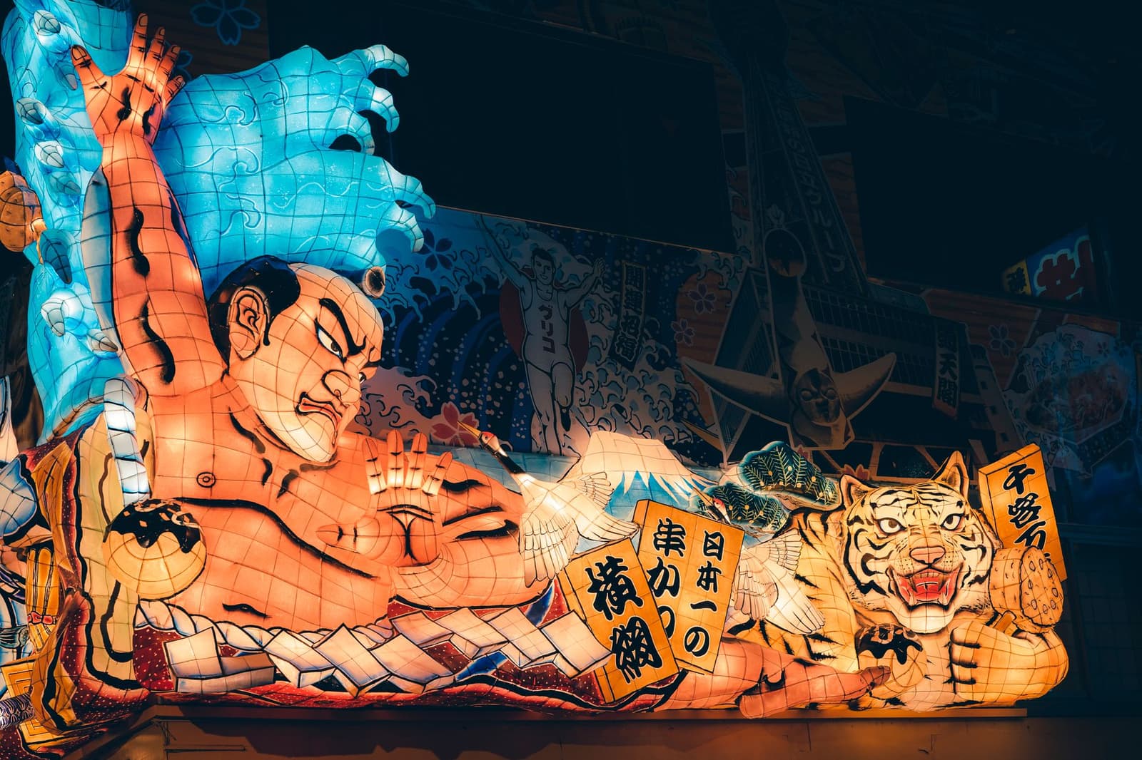 Illuminated Nebuta festival float painted with a warrior and a tiger at night