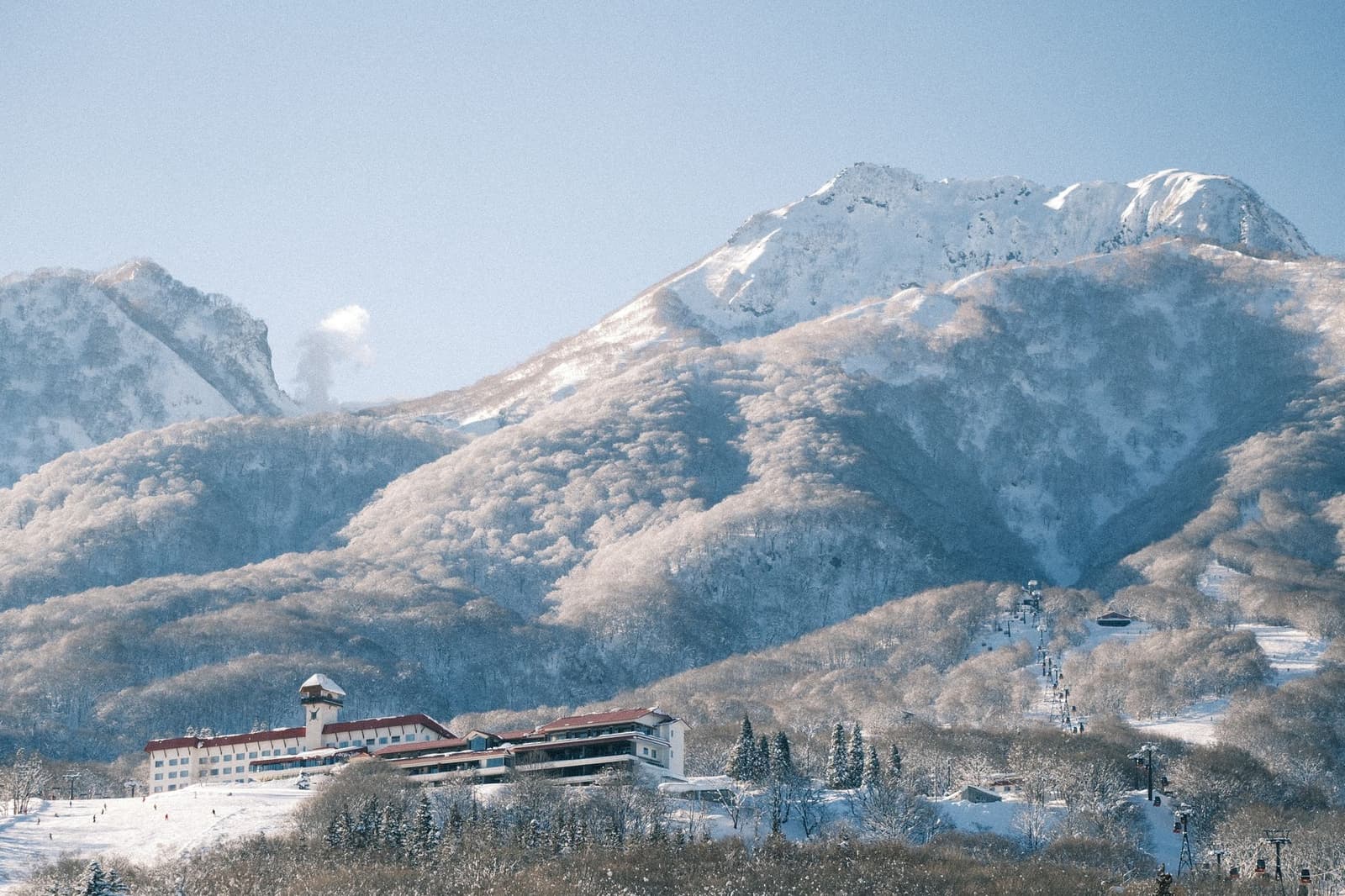 A resort building below snow-covered mountain terrain in the Japanese Alps in winter