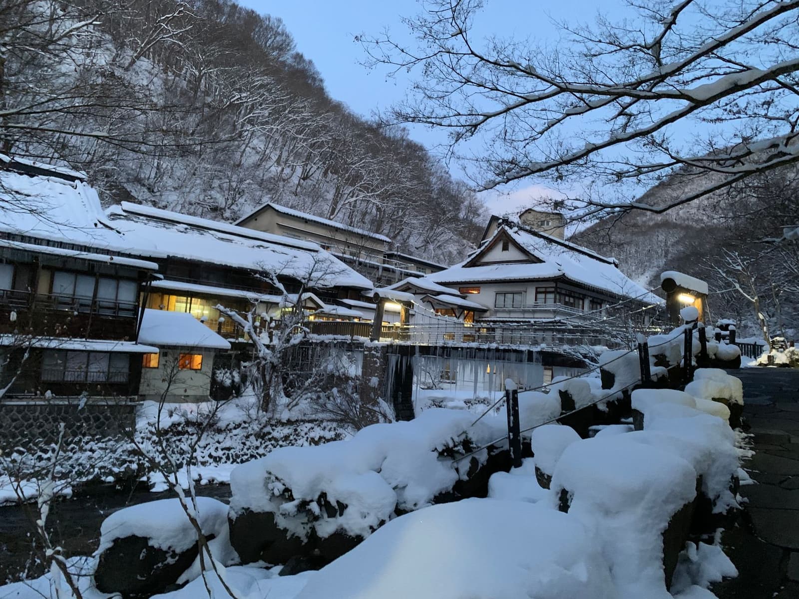 Traditional wooden inn buildings under deep snow with warm window light