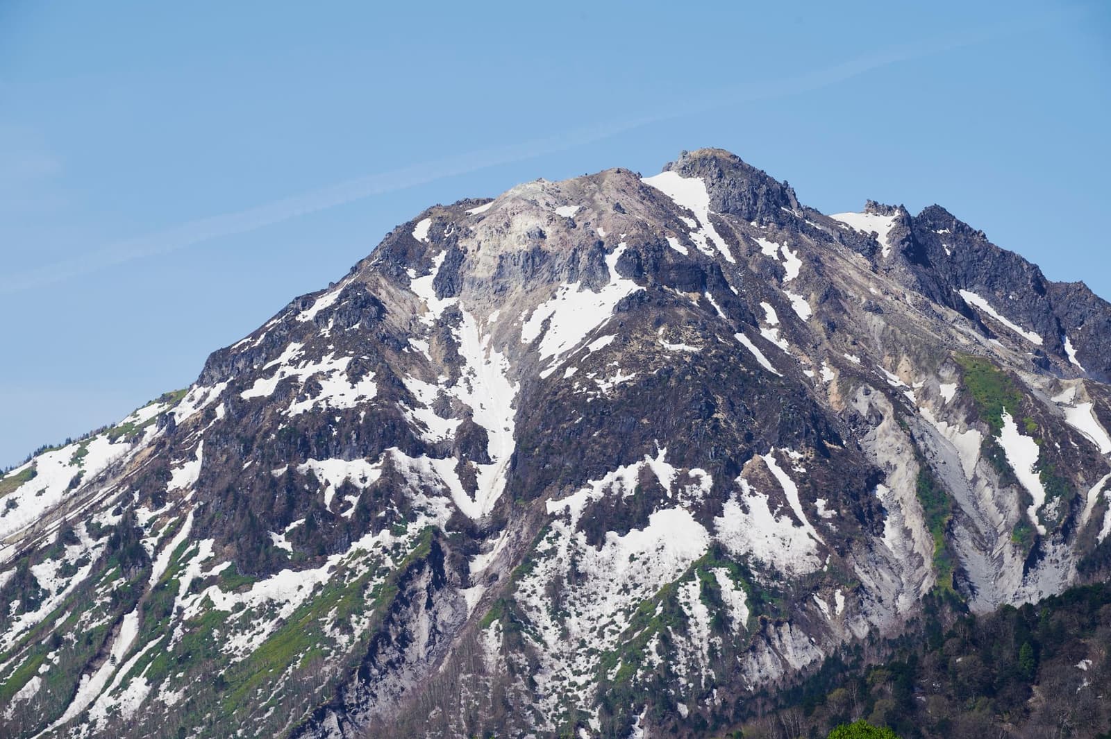 Snow-streaked rocky peak of Mount Norikura in Nagano under a clear sky