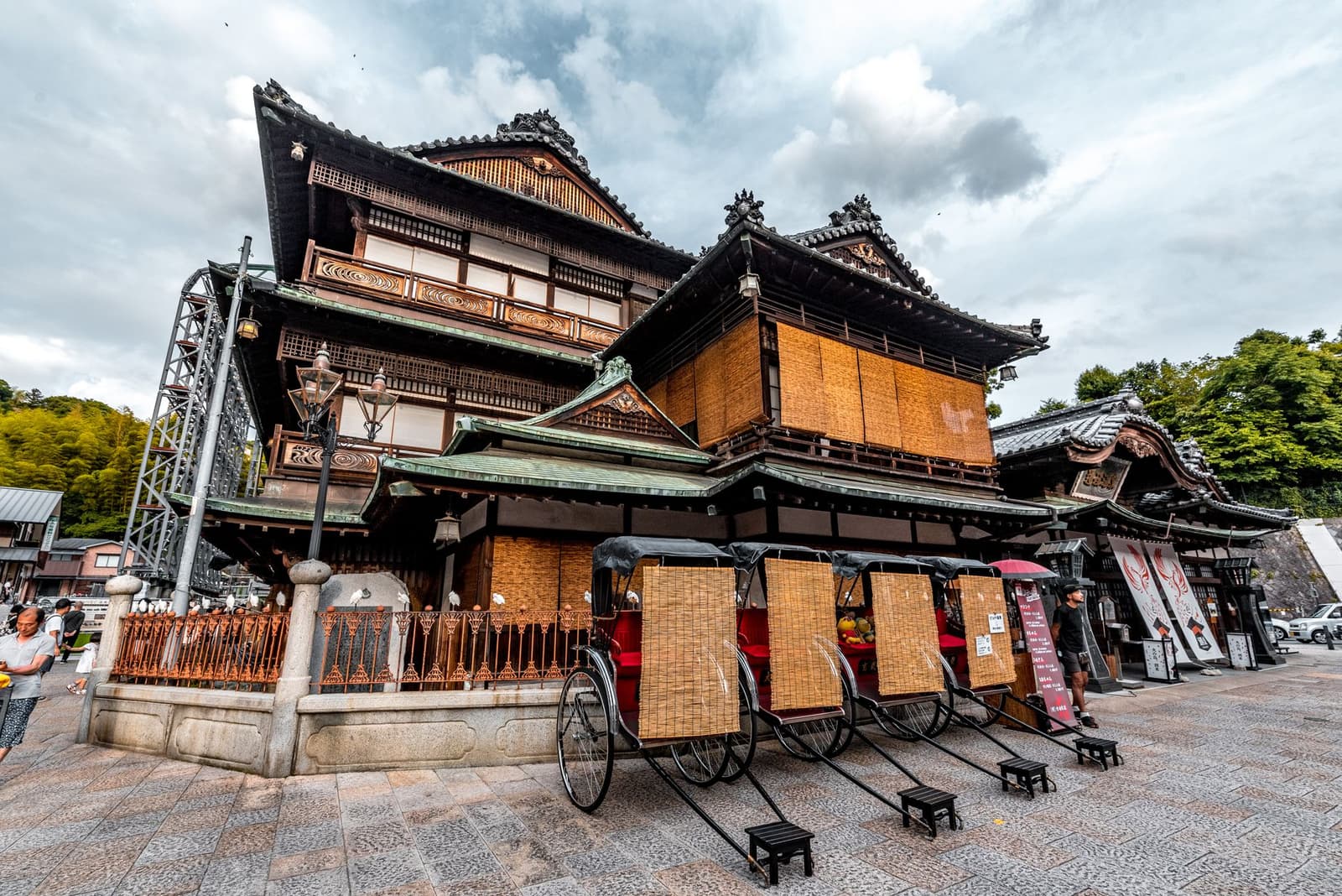 The historic wooden bathhouse at Dogo Onsen with rickshaws waiting outside