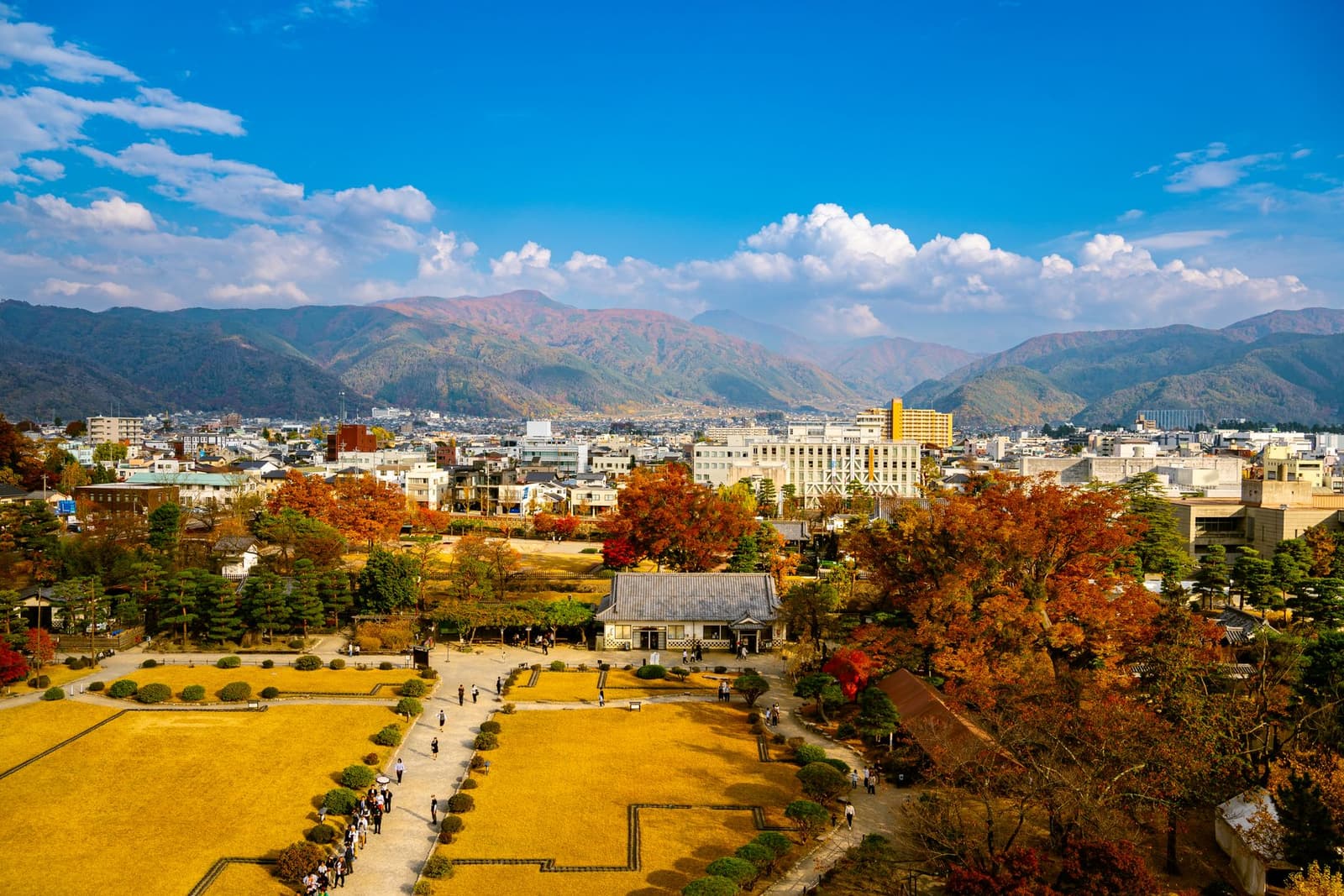 Nagano city and its park under autumn trees with mountains behind
