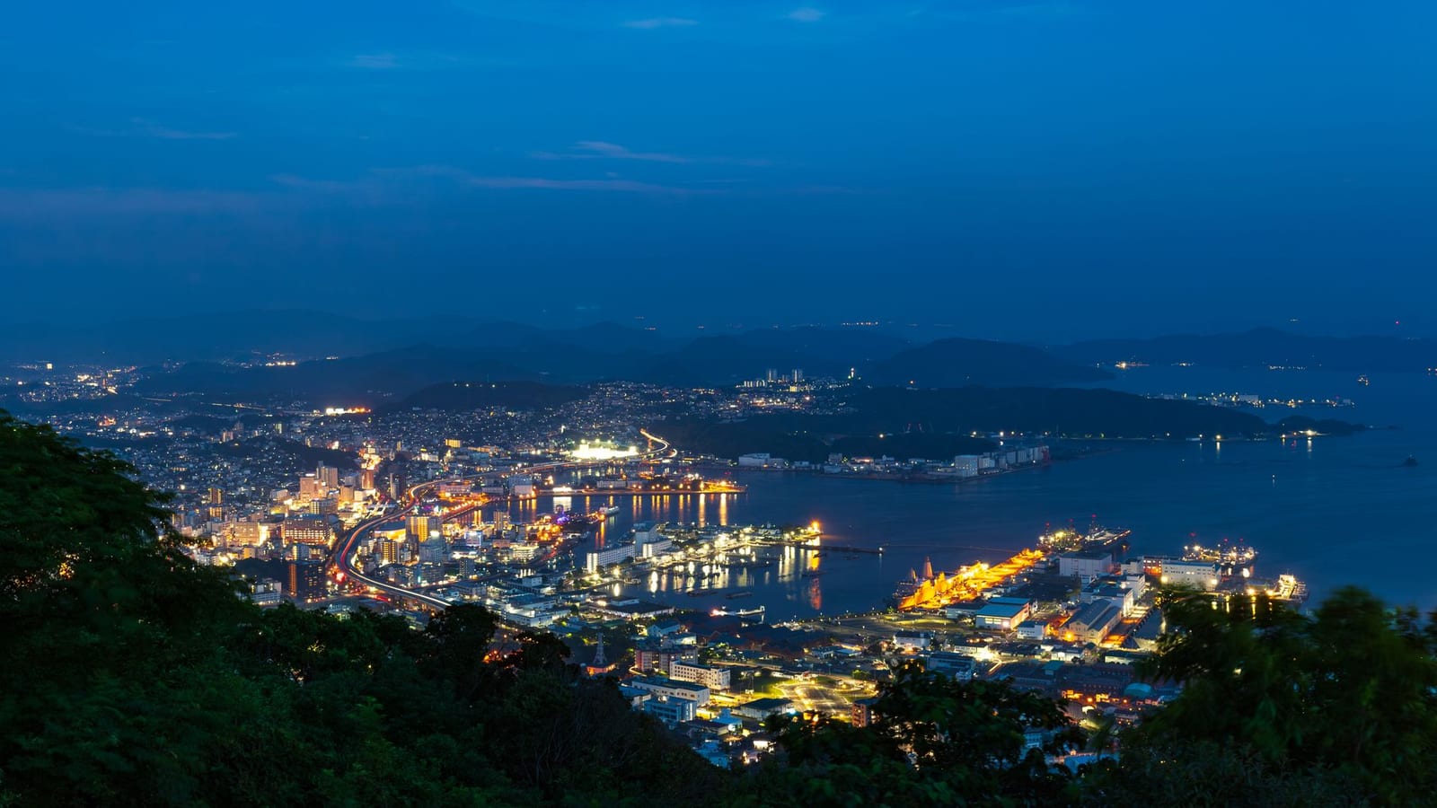 Nagasaki harbour and the illuminated city terraced above it in the evening