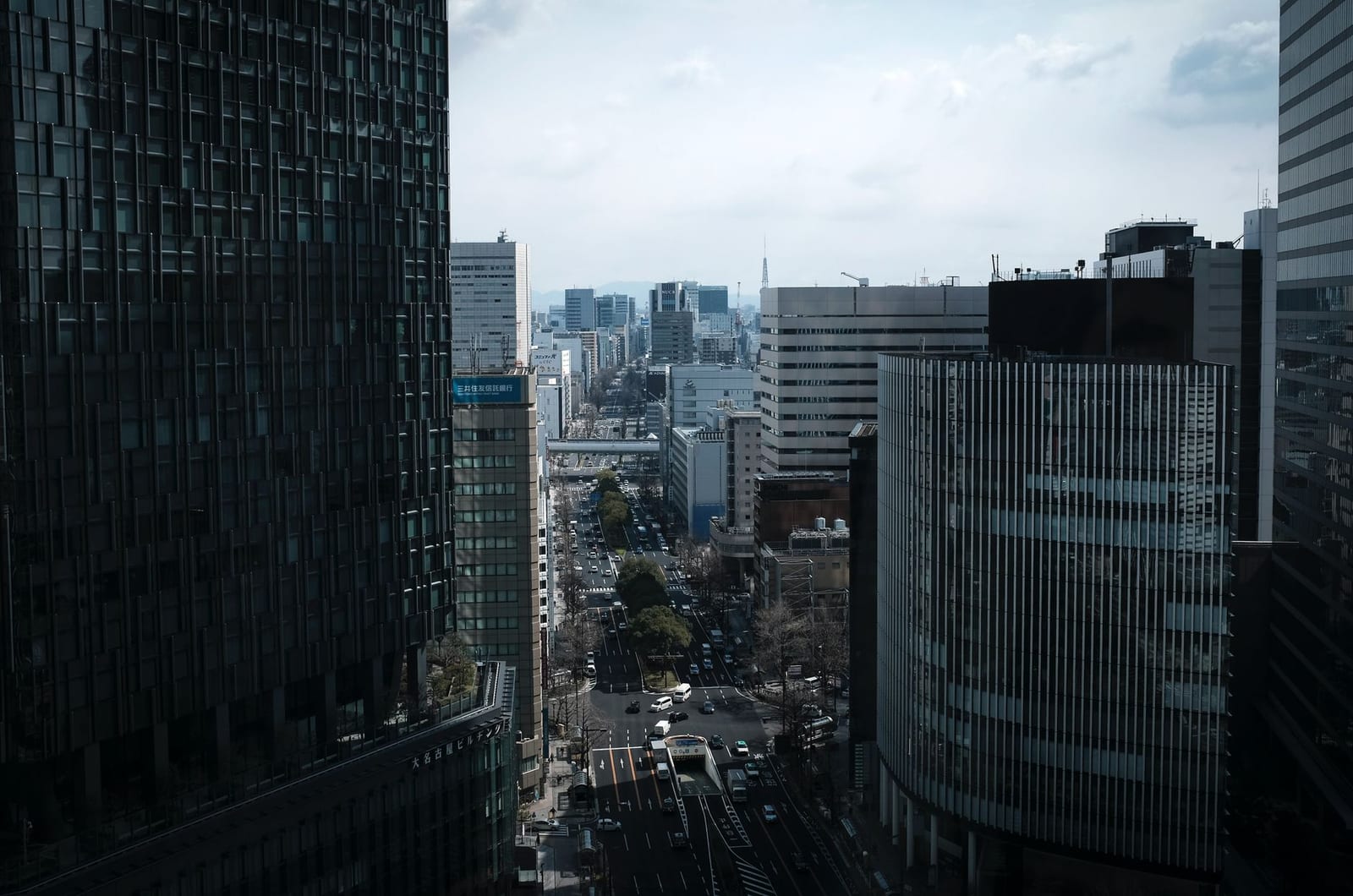 Tall buildings lining a street through central Nagoya on a cloudy day