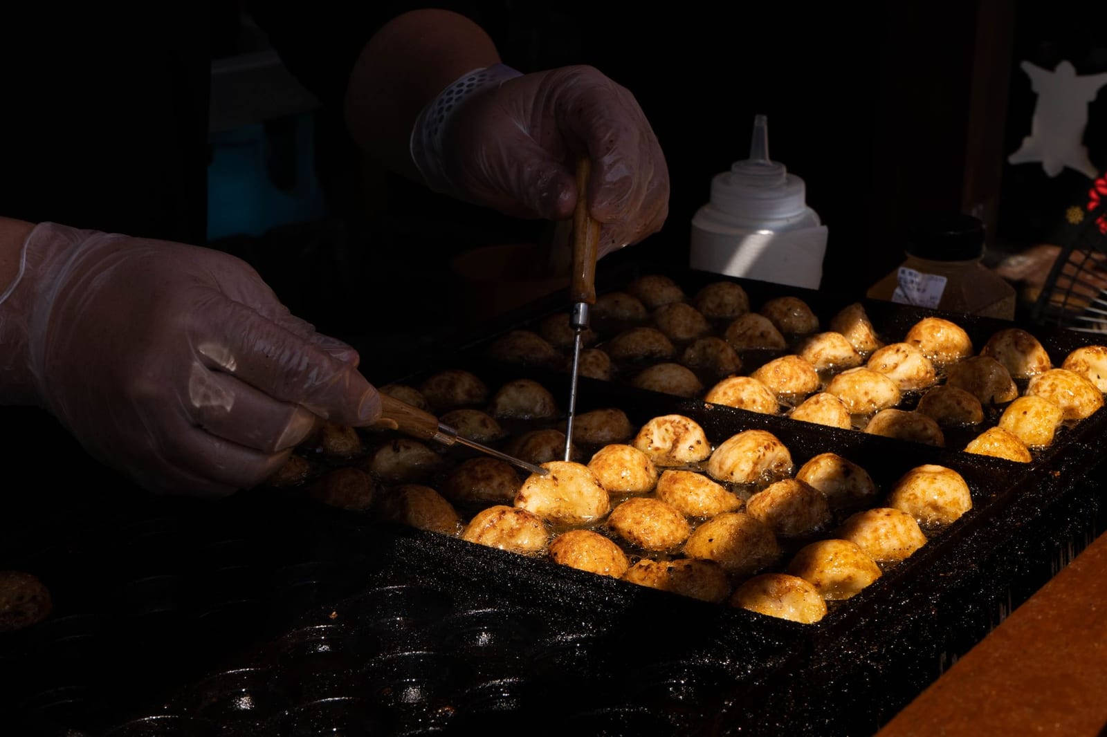 Takoyaki being turned on a hot griddle at a Japanese street food stall
