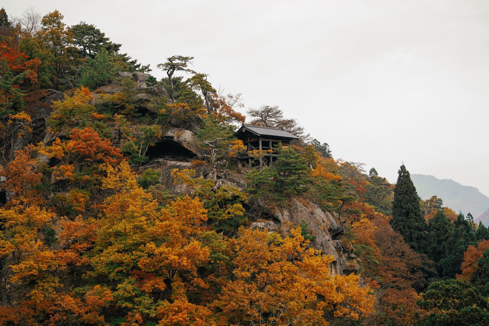 Temple halls set among autumn trees on a rocky mountain ridge